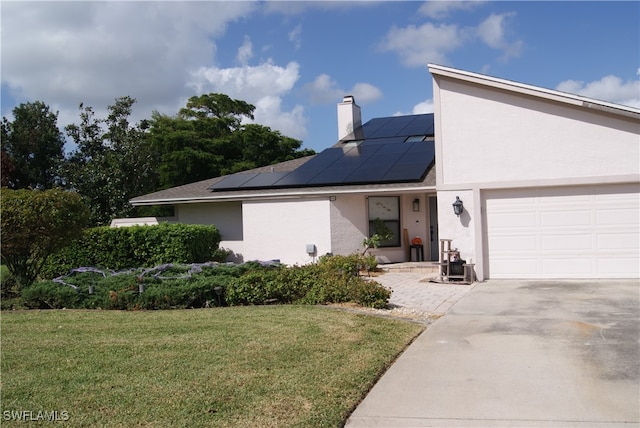 view of front of property featuring solar panels, a garage, and a front lawn