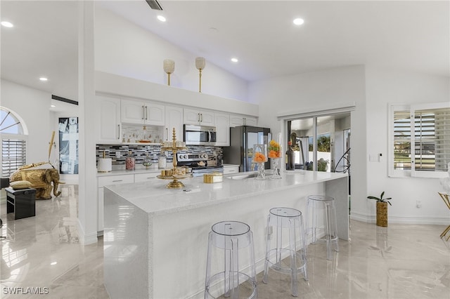 kitchen with white cabinetry, stainless steel appliances, a breakfast bar area, and plenty of natural light