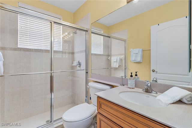 bathroom featuring a healthy amount of sunlight, vanity, toilet, and an enclosed shower