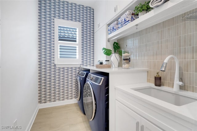 washroom featuring light hardwood / wood-style floors, cabinets, independent washer and dryer, and sink