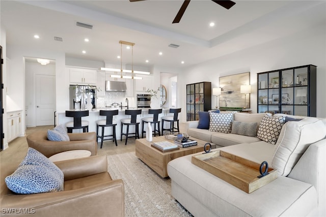 living room with ceiling fan, sink, and light wood-type flooring