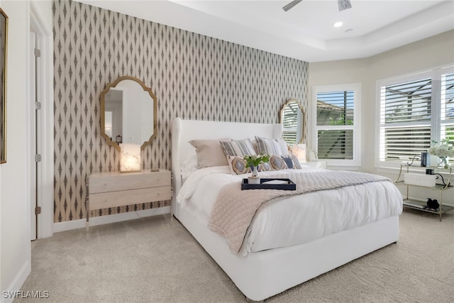 carpeted bedroom with a tray ceiling and ceiling fan