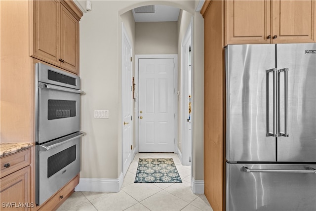 kitchen with light tile patterned floors, stainless steel appliances, and light stone counters