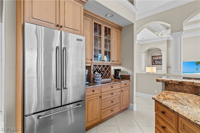 kitchen featuring ornate columns, light stone counters, crown molding, high quality fridge, and light tile patterned floors