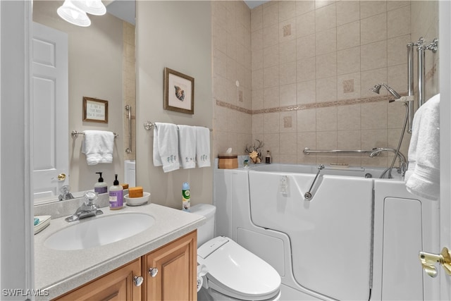 bathroom with a washtub, vanity, and toilet