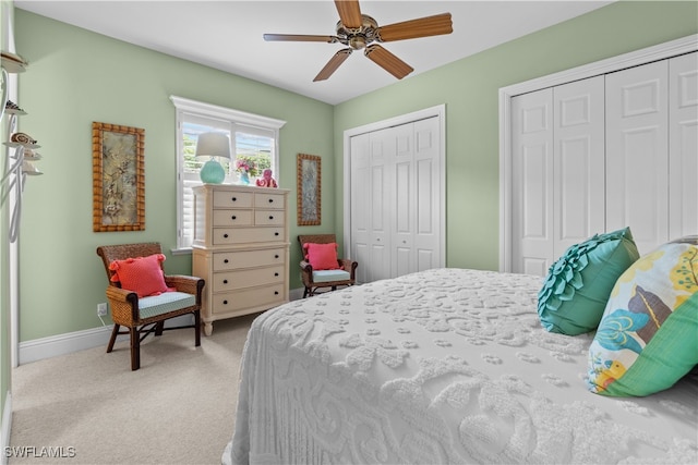 bedroom featuring light carpet, two closets, and ceiling fan