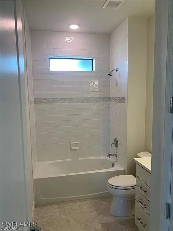 full bathroom with vanity, tiled shower / bath combo, and toilet