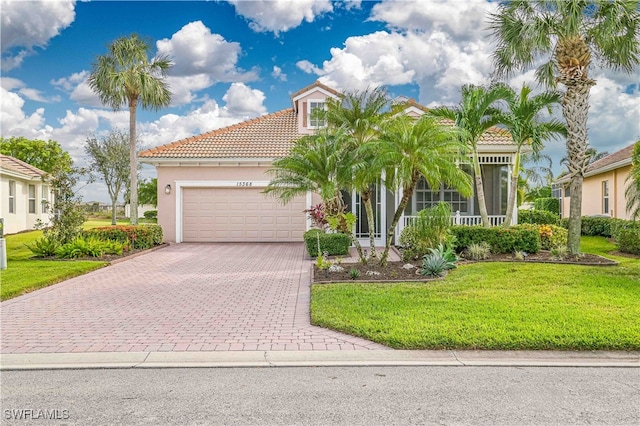 mediterranean / spanish-style home with covered porch, a garage, and a front lawn