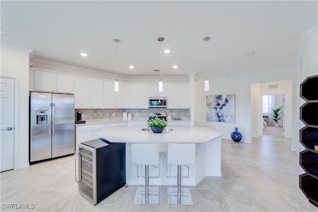 kitchen with hanging light fixtures, a kitchen island, white cabinetry, crown molding, and stainless steel appliances