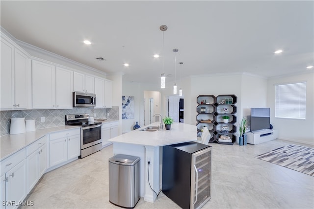 kitchen with appliances with stainless steel finishes, sink, an island with sink, hanging light fixtures, and white cabinets