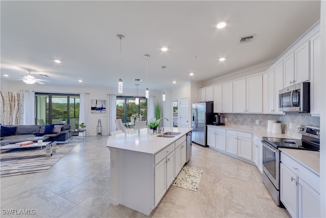 kitchen featuring white cabinets, hanging light fixtures, a center island with sink, sink, and stainless steel appliances