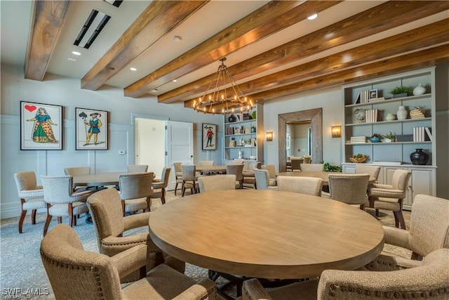 dining area featuring beam ceiling, a chandelier, and built in shelves