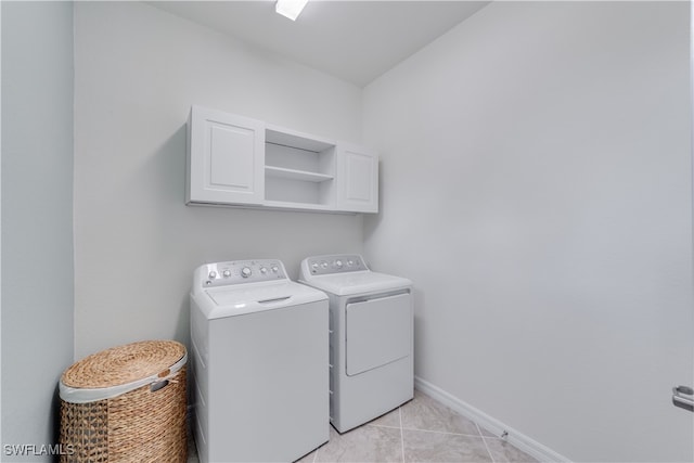 washroom featuring cabinets, light tile patterned flooring, and washing machine and clothes dryer