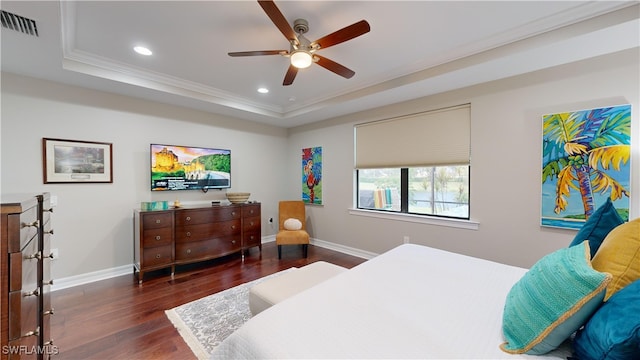 bedroom with ceiling fan, ornamental molding, dark wood-type flooring, and a tray ceiling