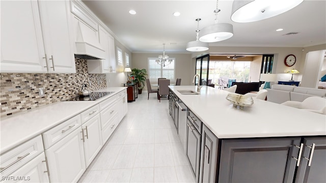 kitchen featuring white cabinets, backsplash, a center island with sink, and sink