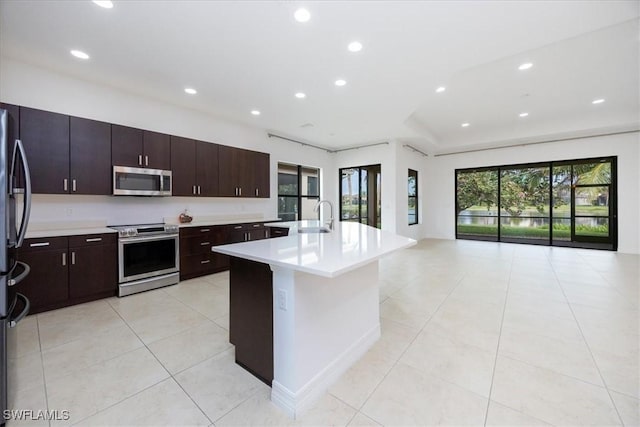 kitchen with appliances with stainless steel finishes, sink, plenty of natural light, and an island with sink