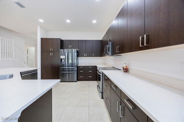 kitchen featuring dark brown cabinets, sink, light tile patterned floors, and stainless steel appliances