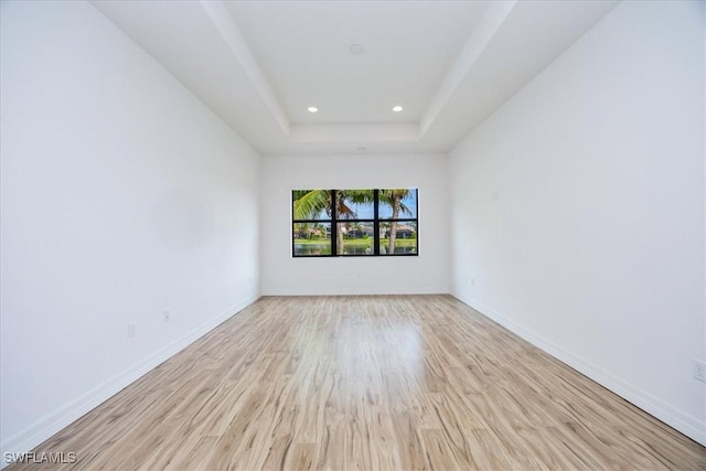 unfurnished room with a raised ceiling and light hardwood / wood-style floors