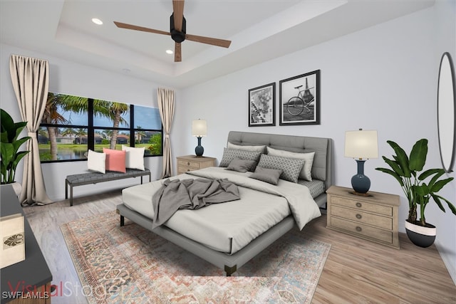 bedroom featuring light hardwood / wood-style floors, a raised ceiling, and ceiling fan