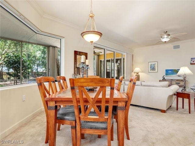 carpeted dining room with ornamental molding and ceiling fan