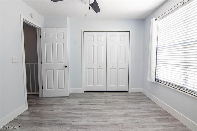 unfurnished bedroom featuring a closet, ceiling fan, light wood-type flooring, and multiple windows