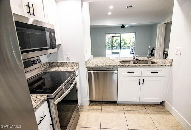 kitchen with kitchen peninsula, appliances with stainless steel finishes, sink, white cabinetry, and light tile patterned floors