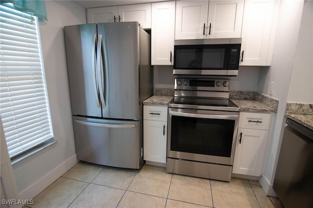 kitchen featuring light stone counters, light tile patterned floors, white cabinets, and stainless steel appliances