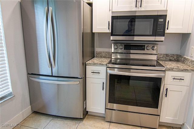 kitchen featuring stainless steel appliances, white cabinetry, light stone counters, and light tile patterned floors