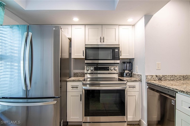 kitchen featuring light stone counters, white cabinets, and stainless steel appliances