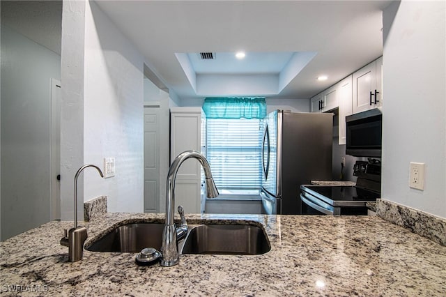 kitchen with sink, stainless steel appliances, white cabinets, and light stone countertops