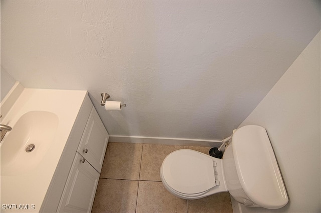 bathroom with toilet, vanity, and tile patterned flooring