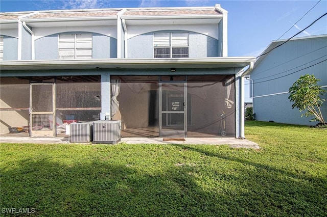 back of property with central AC, a yard, and a sunroom