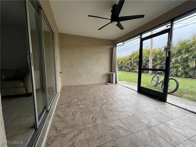 unfurnished sunroom featuring ceiling fan