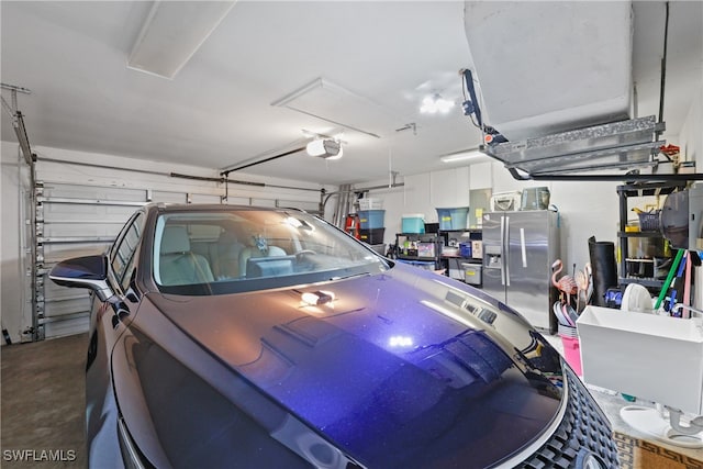 garage with a garage door opener and stainless steel refrigerator with ice dispenser