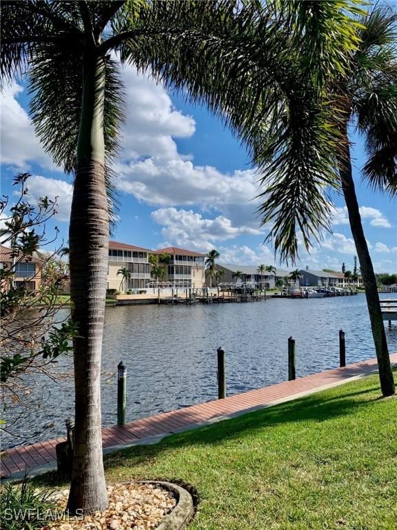 view of dock with a water view and a yard