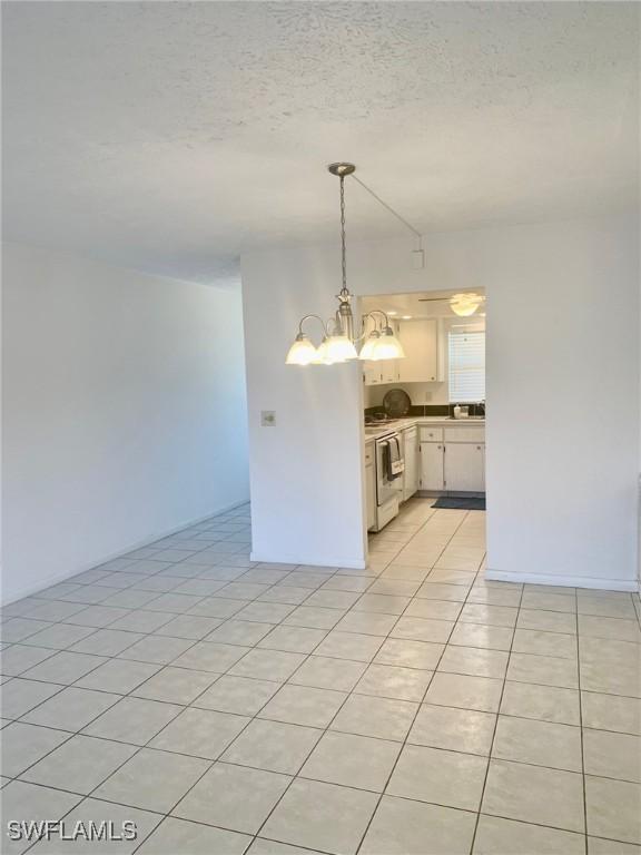 interior space featuring white cabinetry, a textured ceiling, light tile patterned floors, electric range, and pendant lighting