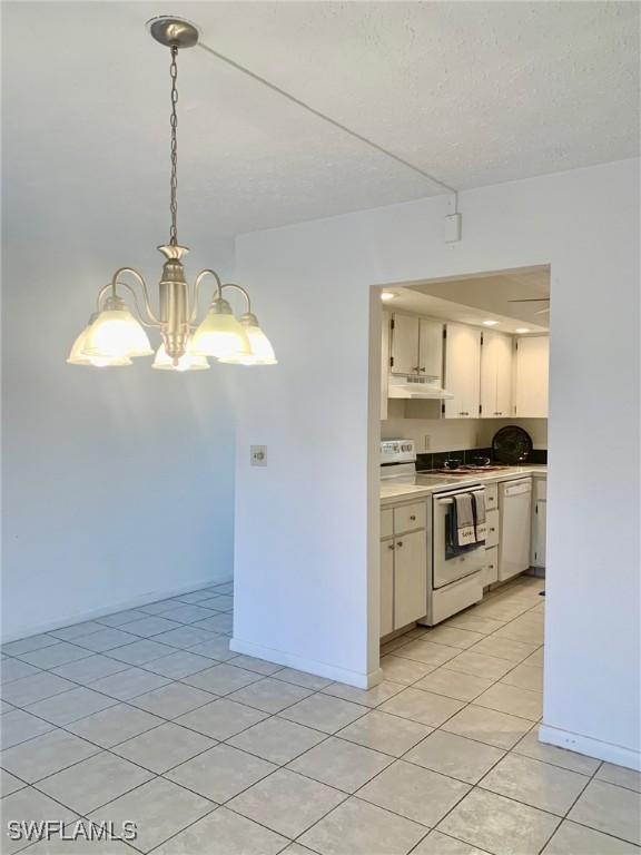 kitchen featuring pendant lighting, a chandelier, white appliances, light tile patterned floors, and a textured ceiling