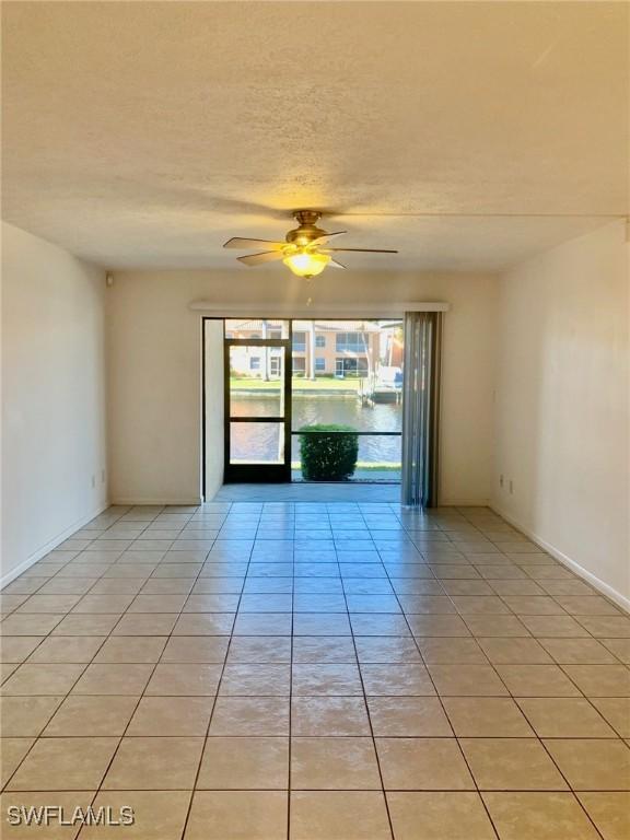 unfurnished room featuring light tile patterned floors, a textured ceiling, and ceiling fan