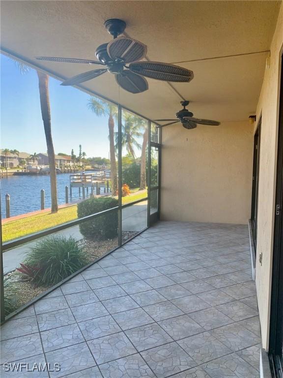 unfurnished sunroom featuring a water view and ceiling fan