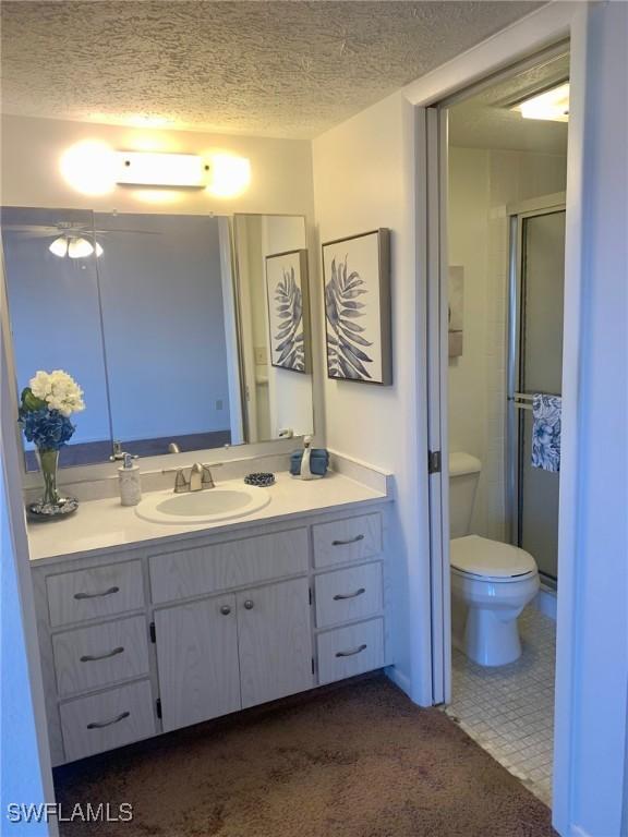 bathroom featuring vanity, toilet, a textured ceiling, and walk in shower