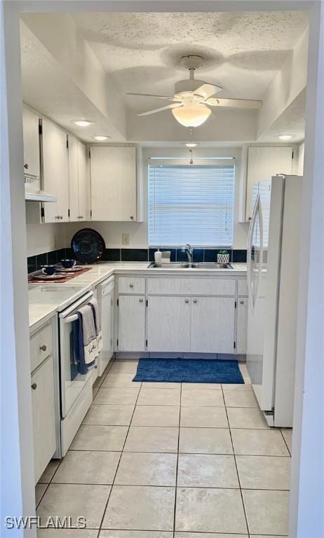 kitchen with white cabinets, white appliances, sink, and light tile patterned floors