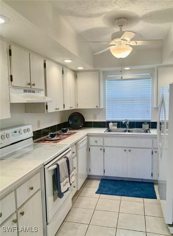 kitchen featuring light tile patterned flooring, sink, a textured ceiling, ceiling fan, and white appliances