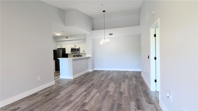 interior space featuring white cabinets, light wood-type flooring, a high ceiling, and black refrigerator