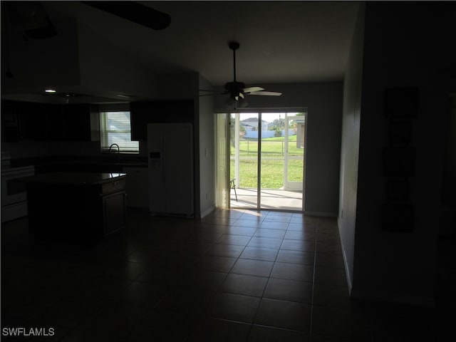 kitchen with a wealth of natural light, vaulted ceiling, dark tile patterned floors, and white fridge with ice dispenser