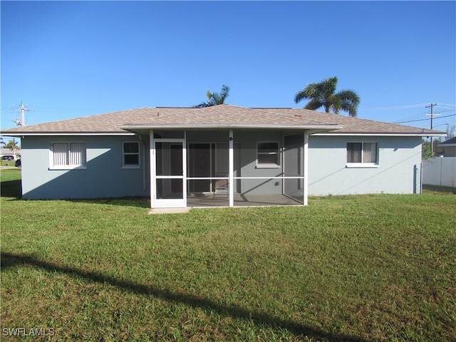 rear view of property with a sunroom and a lawn