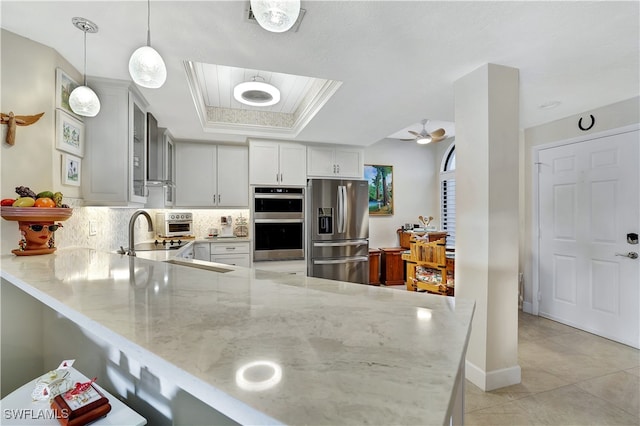 kitchen with decorative light fixtures, kitchen peninsula, stainless steel appliances, and ceiling fan