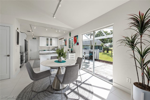 dining space featuring lofted ceiling, light tile patterned flooring, and track lighting