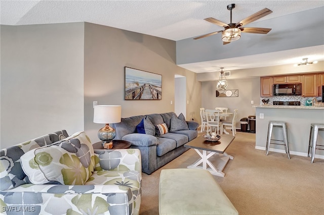 carpeted living room featuring ceiling fan and a textured ceiling