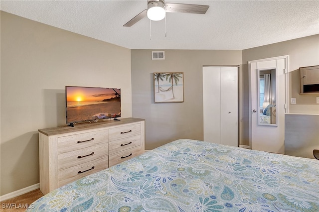 carpeted bedroom featuring ceiling fan, a textured ceiling, and a closet