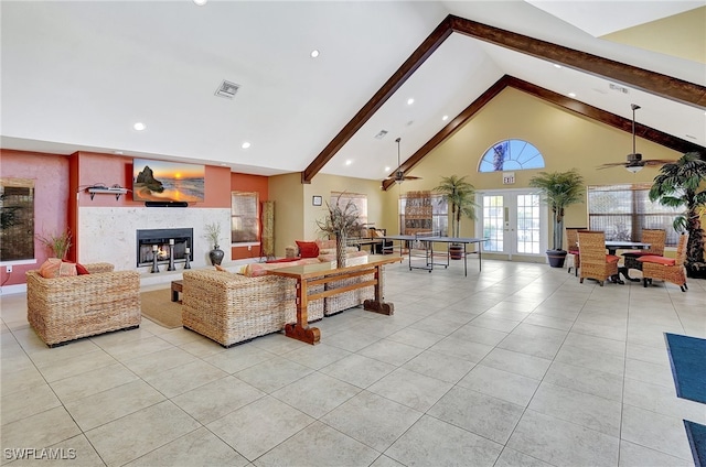 tiled living room featuring ceiling fan, french doors, a high end fireplace, beamed ceiling, and high vaulted ceiling